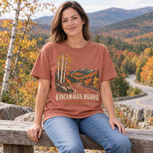 Woman wearing a Yam Kancamagus Highway Autumn Road graphic tee during a fall stop in New Hampshire