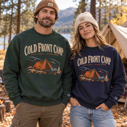 Man and woman wearing Cold Front Camp unisex graphic sweatshirts in Dark Green and Navy at an autumn campsite
