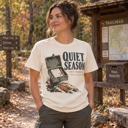 Woman wearing an Ivory Quiet Season Trail Register graphic tee in a fall hiking setting