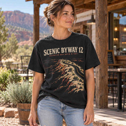Woman wearing a black Scenic Byway 12 graphic T-shirt outdoors, featuring a winding highway through Utah red rock formations.