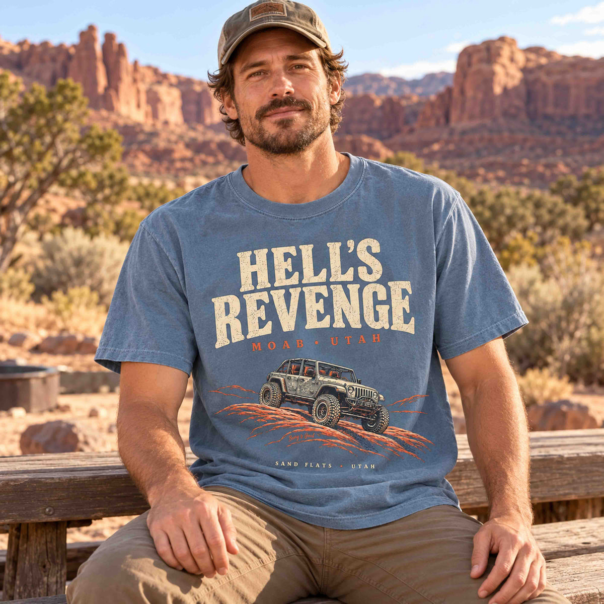 Woman wearing a Blue Jean Hell’s Revenge Moab graphic t-shirt with cream lettering and orange slickrock artwork.