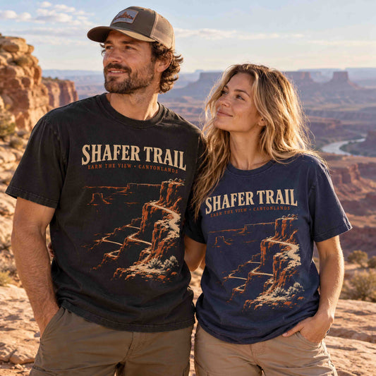 Couple wearing Black and Navy Shafer Trail Canyonlands graphic T-shirts at a Utah canyon overlook.