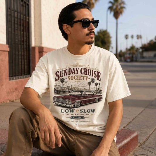 Seated man wearing a Sunday Cruise Society Southern California lowrider graphic tee