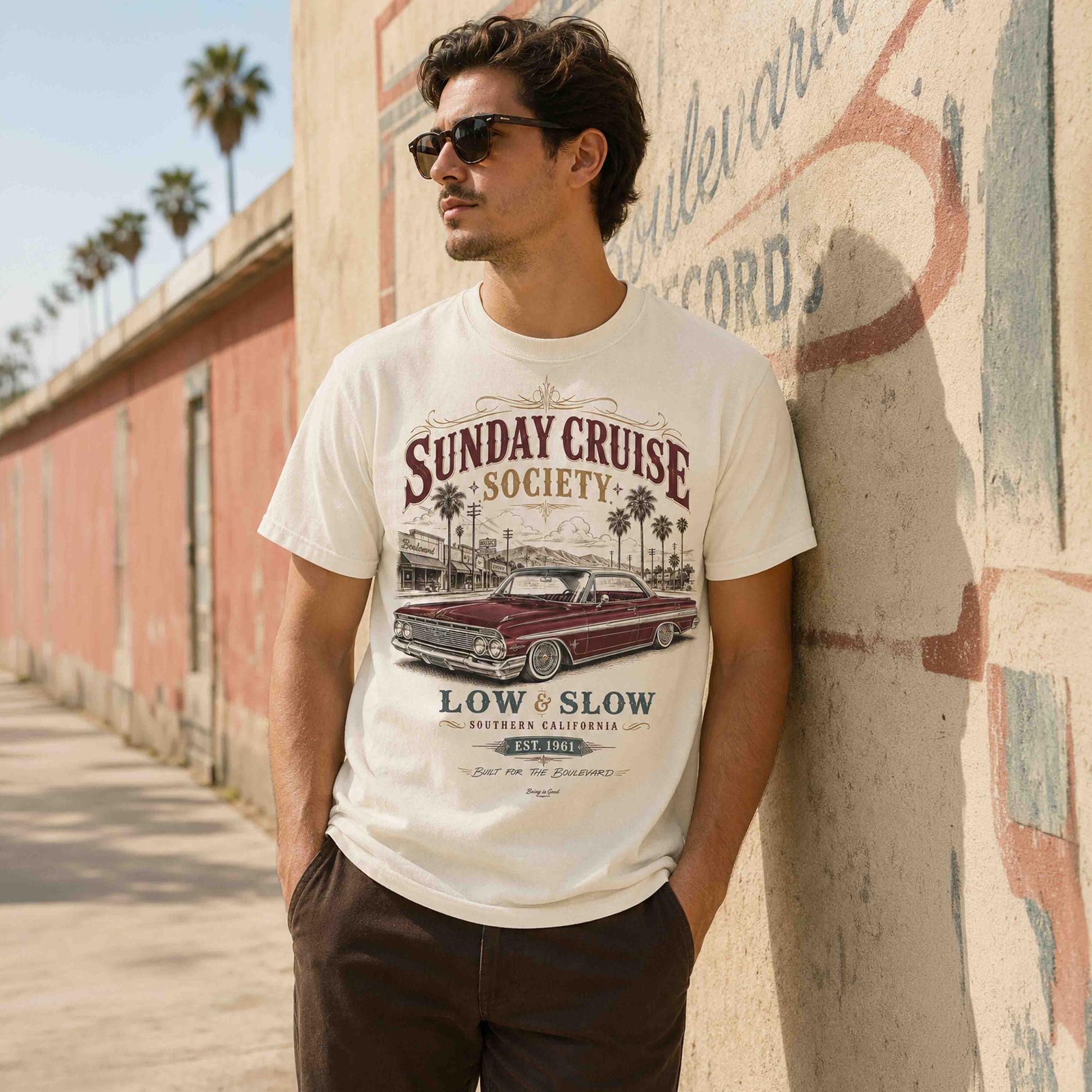 Man wearing an Ivory Low and Slow classic car T-shirt beside a vintage boulevard wall