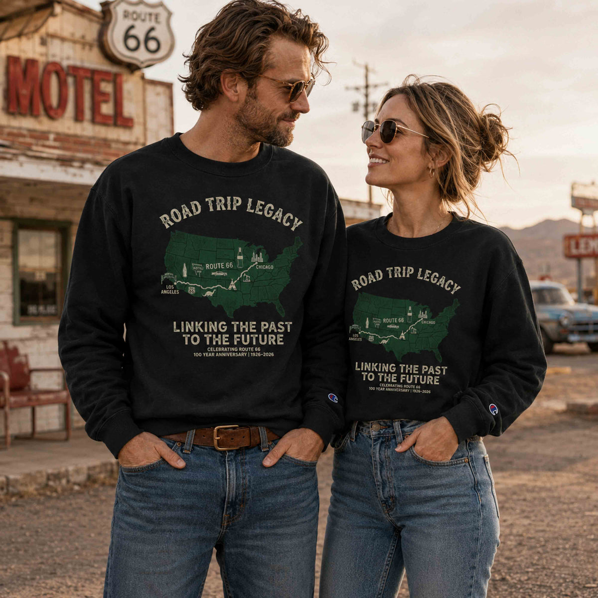 Couple wearing black Champion Powerblend Route 66 Road Trip Legacy graphic sweatshirts at a vintage roadside motel