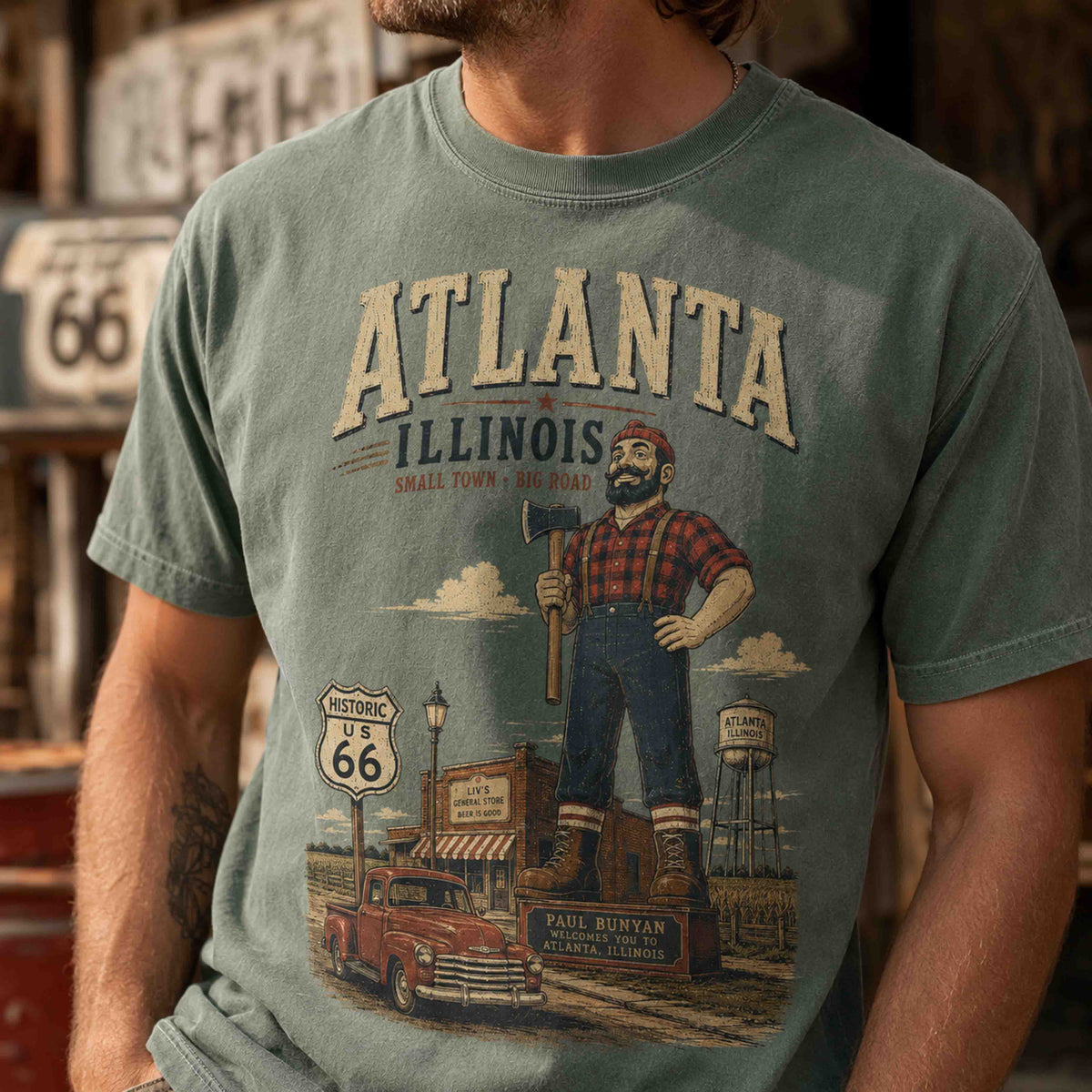 Folded Atlanta Illinois Route 66 Historic Downtown graphic tees in Moss and Yam with vintage roadside styling