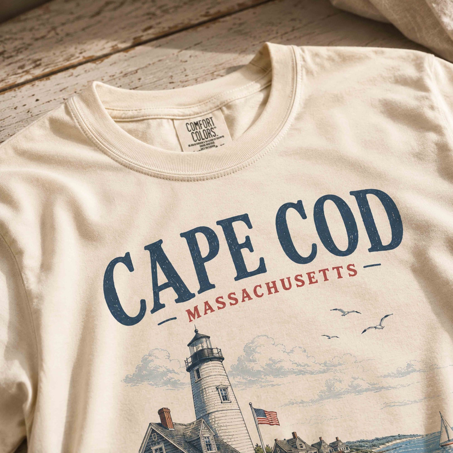 Close-up of Ivory Cape Cod graphic tee showing lighthouse and coastal artwork