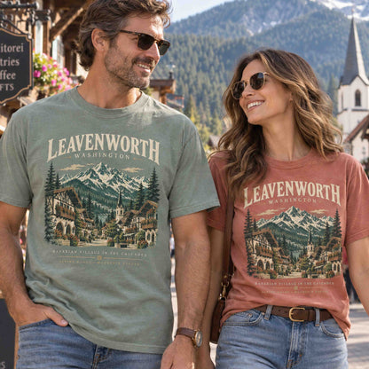 Couple wearing Moss green and Yam Leavenworth Washington graphic tees with Bavarian village and Cascade Mountains artwork.
