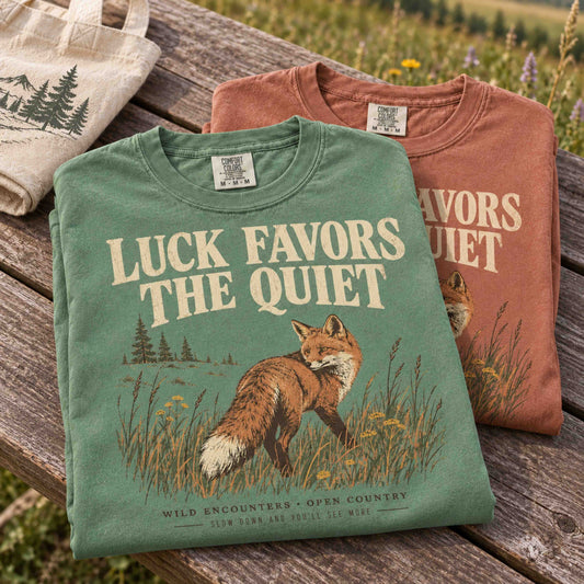 Luck Favors the Quiet fox wildlife graphic tee featuring a red fox in tall meadow grass with vintage outdoor artwork.