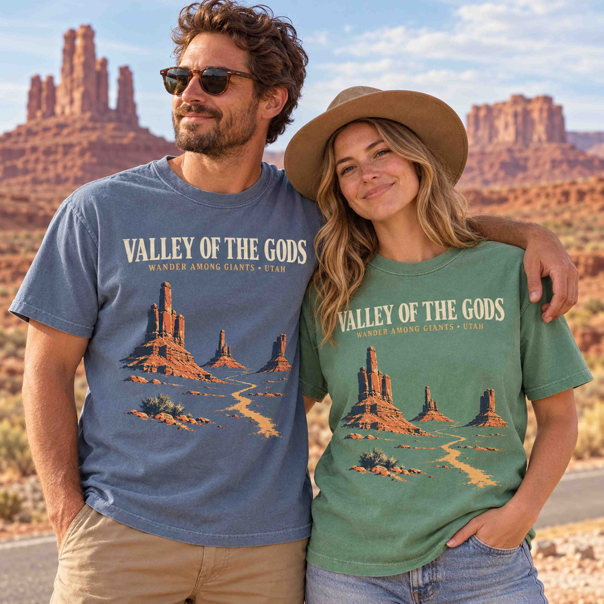 Couple wearing Blue Jean and Light Green Valley of the Gods Utah graphic T-shirts with sandstone formations and desert road artwork.