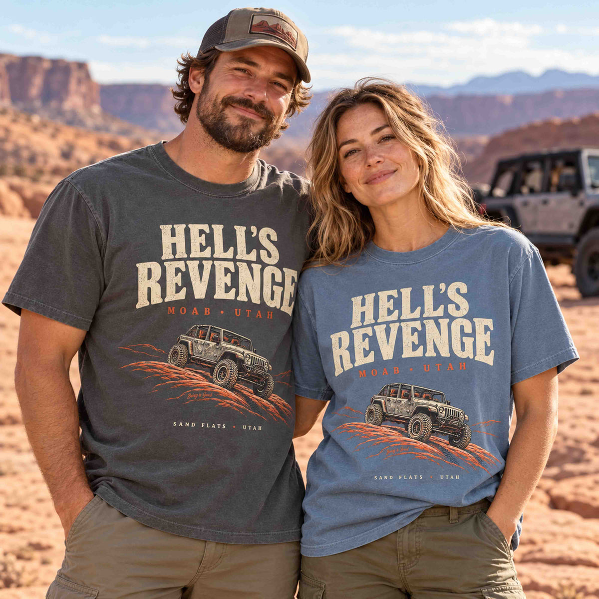 Couple wearing Hell’s Revenge Moab graphic t-shirts in Pepper and Blue Jean against a red rock desert backdrop.