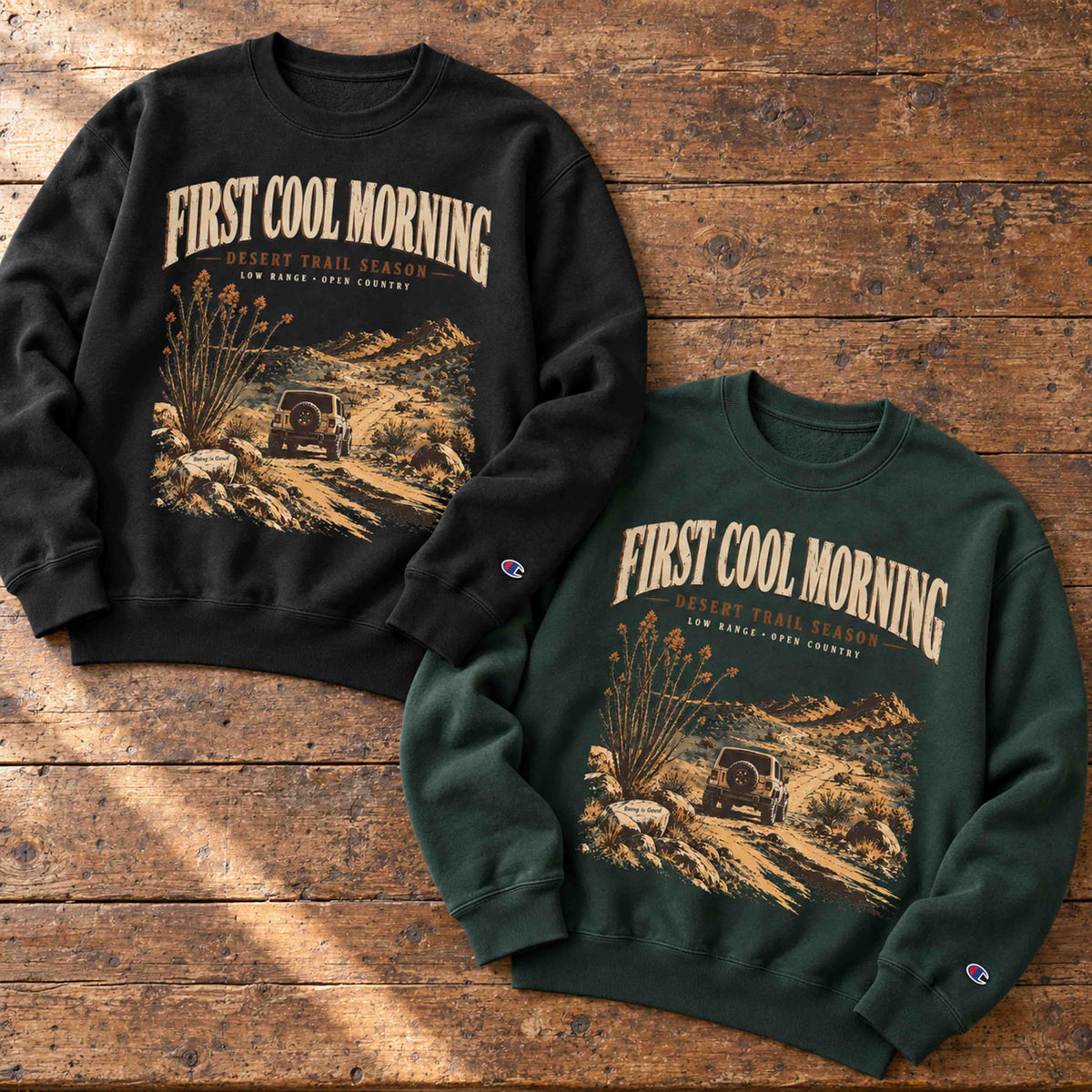 Black and Dark Green Champion First Cool Morning Desert Trail graphic sweatshirts displayed on aged wood