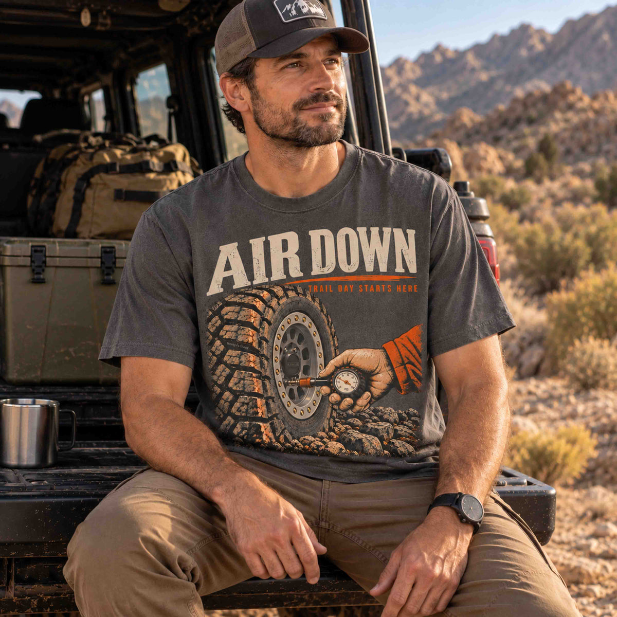 Air Down graphic tee by Being is Good in Pepper, seated men's fit beside trail gear