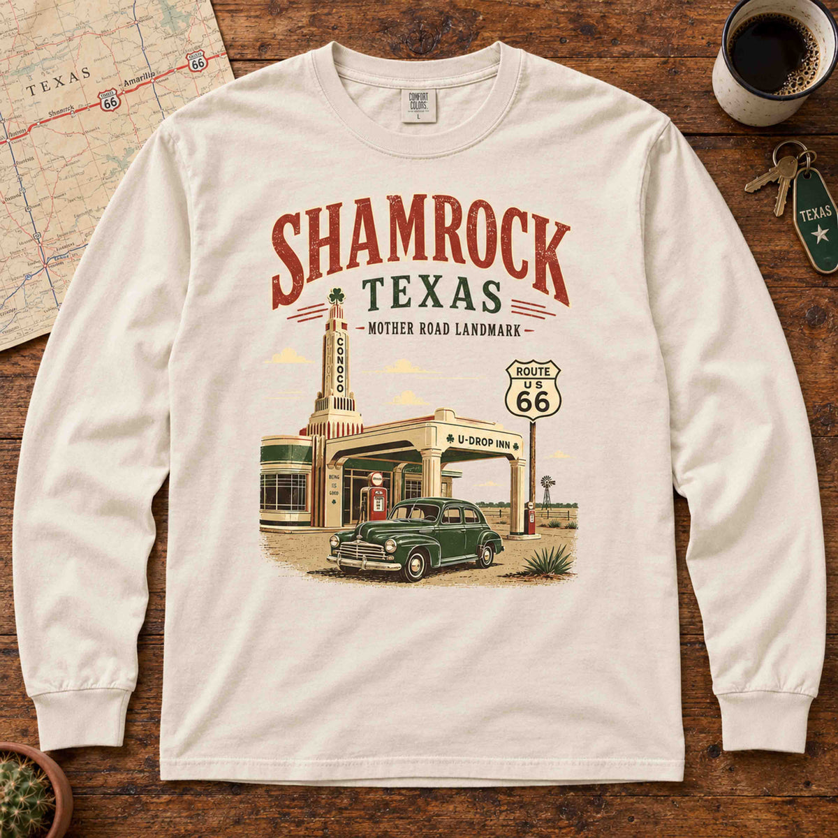 Ivory Shamrock Texas Route 66 long sleeve tee laid flat beside a Texas map and coffee, showing U-Drop Inn and classic car artwork.