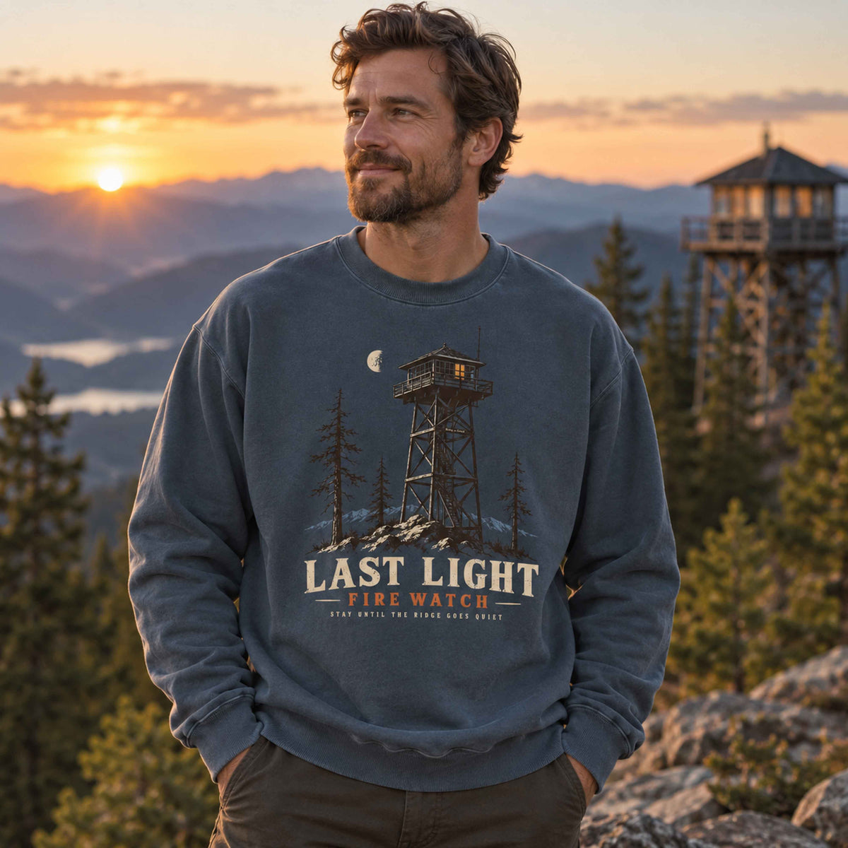 Denim Last Light Fire Watch graphic sweatshirt in a mountain wilderness setting at dusk