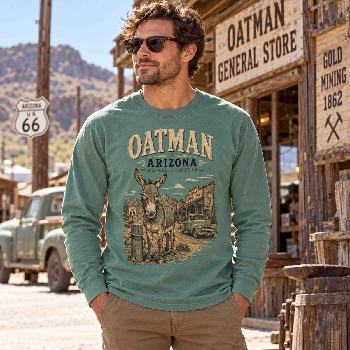 Man wearing a Light Green Oatman Arizona Route 66 burro long sleeve tee beside an Old West storefront.