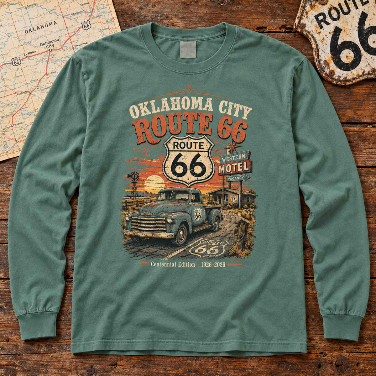 Light Green Oklahoma City Route 66 long sleeve tee laid flat on wood, showing vintage truck, motel sign and centennial artwork.