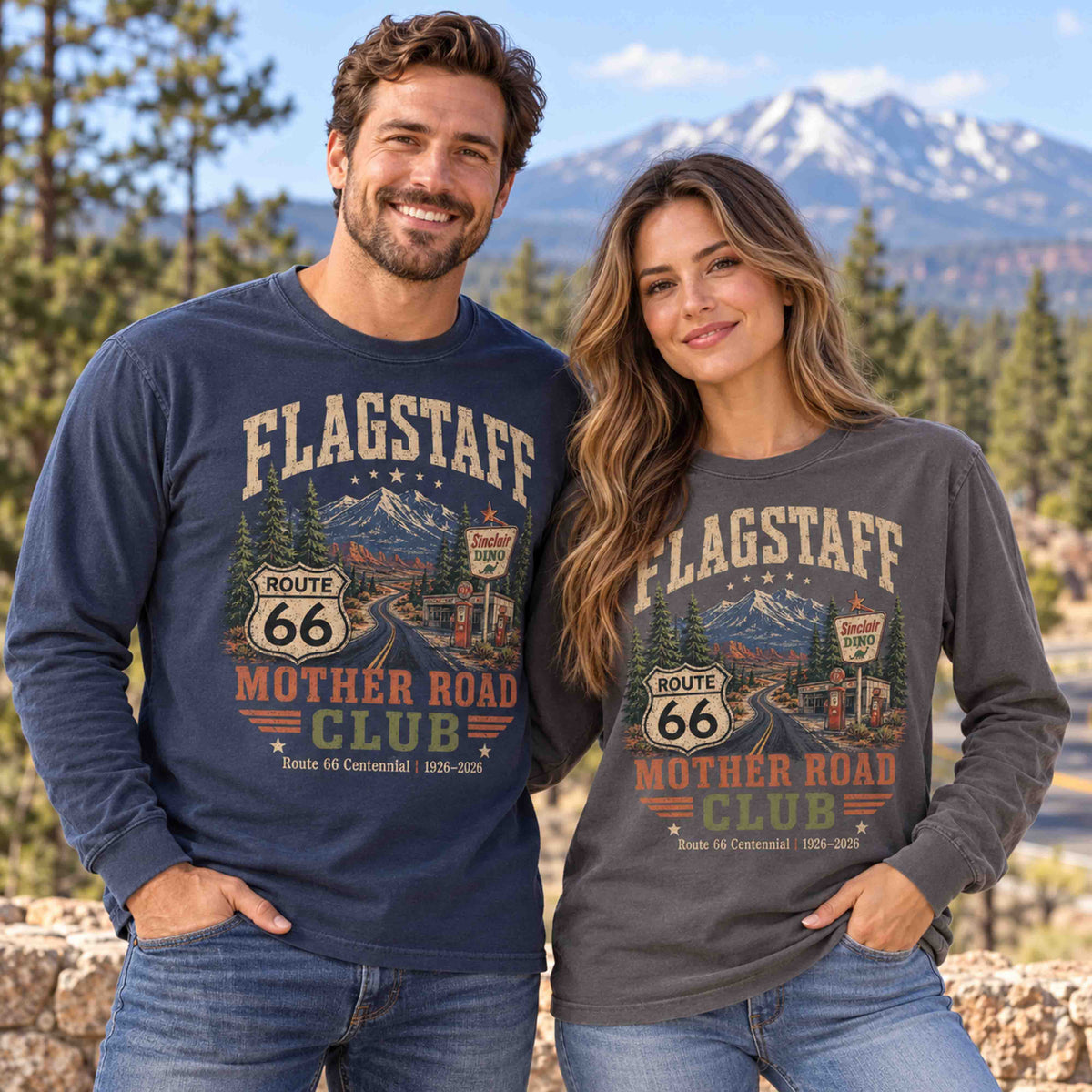 Man in Navy and woman in Pepper wearing Flagstaff Route 66 Mother Road Club long sleeve tees in a pine forest with mountains behind them.