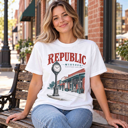 Woman seated on a wooden bench wearing a White Republic Missouri Main Street graphic T-shirt.