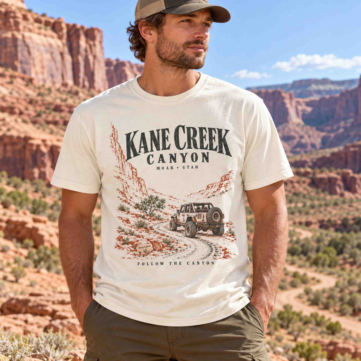 Man seated outdoors wearing the White Kane Creek Canyon graphic tee.