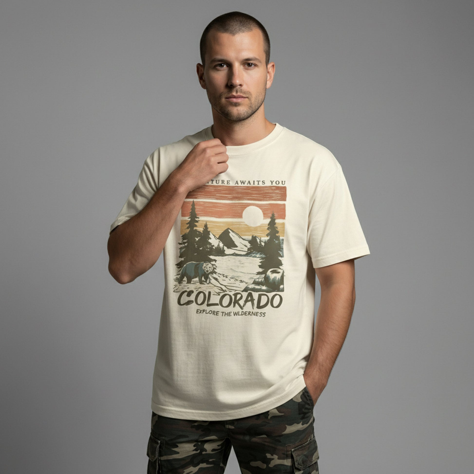 Front view of a man modeling a cream everyday-fit t-shirt with a retro Colorado mountain illustration.
