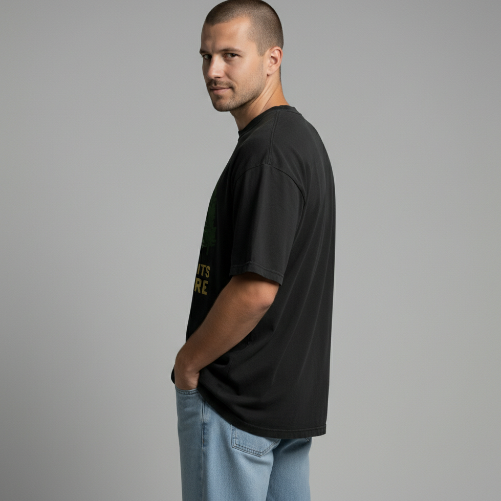 Side profile view of a man looking back over his shoulder, modeling a black outdoor lifestyle t-shirt.