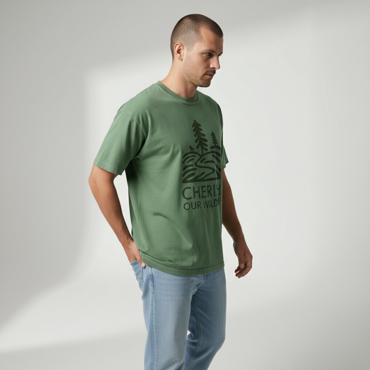 Side angle view of a man looking down thoughtfully, wearing a green minimalist graphic t-shirt.