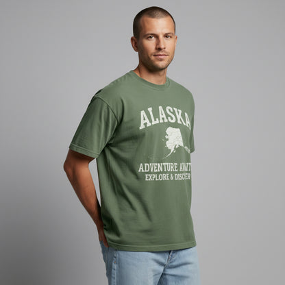 Side angle view of a man wearing a green minimalist Alaska t-shirt.