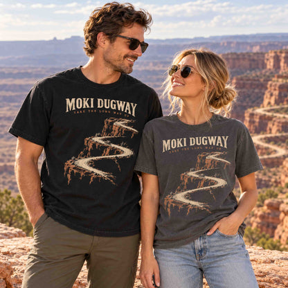 Couple wearing Black and Pepper Moki Dugway Utah graphic T-shirts at a desert canyon overlook.