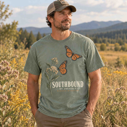 Man wearing a Moss Southbound by Instinct monarch butterfly graphic T-shirt and a cap in a meadow.