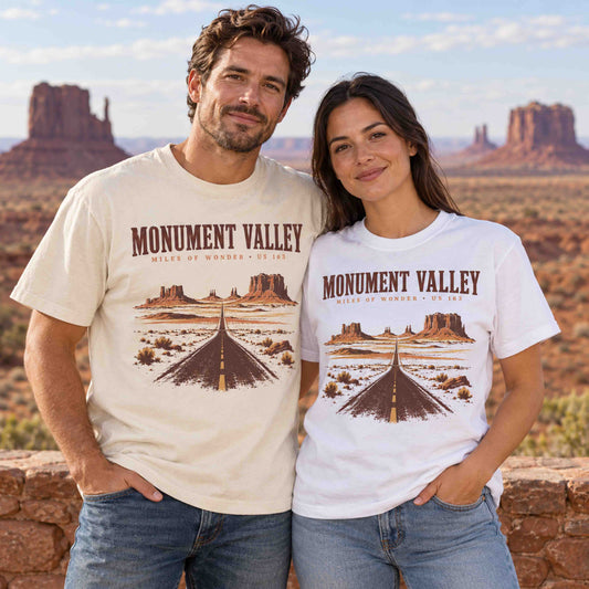 Couple wearing Ivory and White Monument Valley graphic tees with vintage US Highway 163 desert road and sandstone buttes artwork.