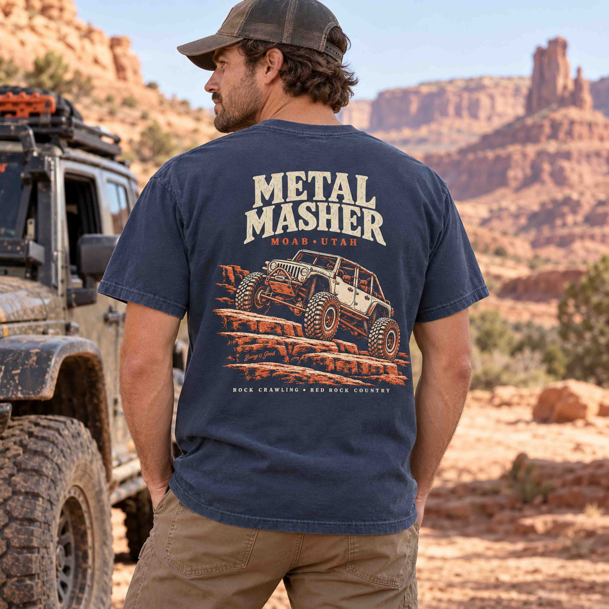 Man wearing a Navy Metal Masher Moab tee, showing the large rock-crawling back graphic beside an off-road vehicle.