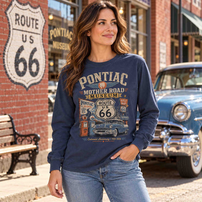 Woman wearing a Navy Pontiac Illinois Route 66 long sleeve graphic tee beside a highway mural and classic car.