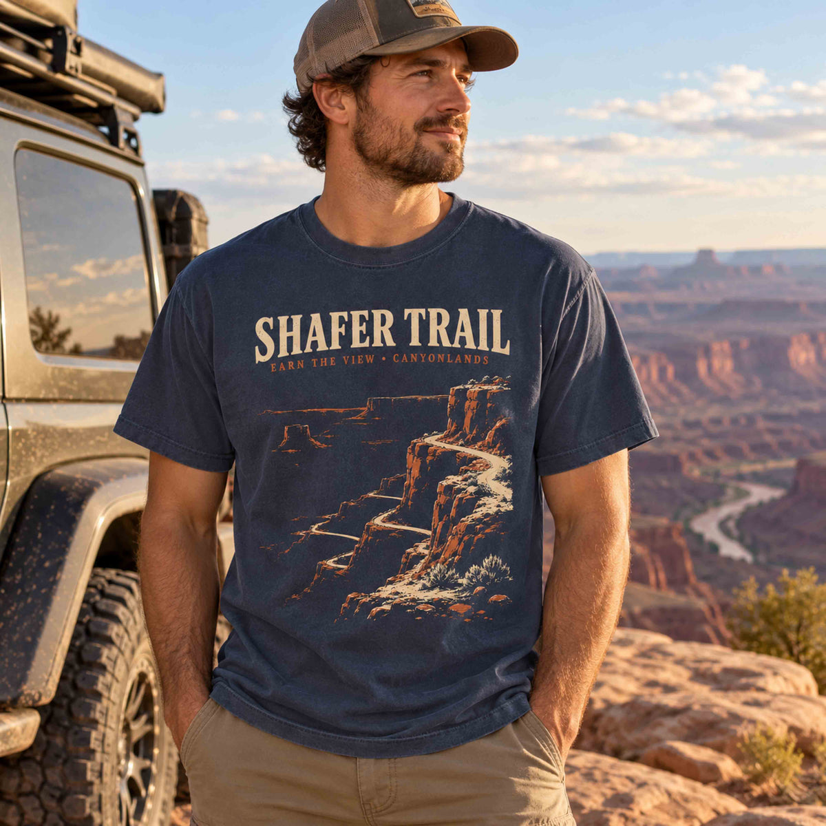 Man wearing a Navy Shafer Trail Canyonlands graphic T-shirt at a Utah canyon overlook.