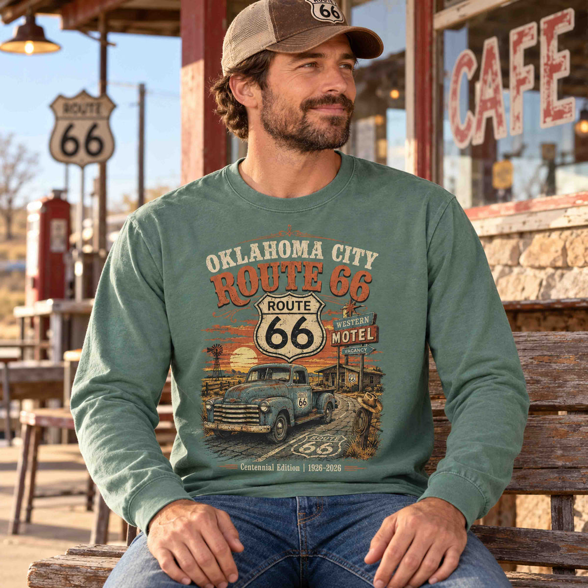 Man seated on a bench wearing a Light Green Oklahoma City Route 66 long sleeve graphic tee outside a cafe.