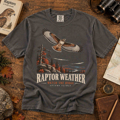 Navy and Pepper Raptor Weather Autumn Flyway graphic tees displayed in a birdwatching field station flat lay