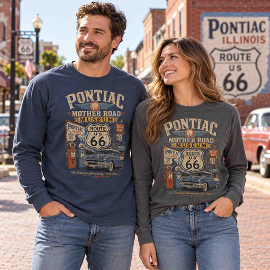 Man in Navy and woman in Pepper wearing Pontiac Illinois Route 66 long sleeve graphic tees with classic car and gas pump artwork.
