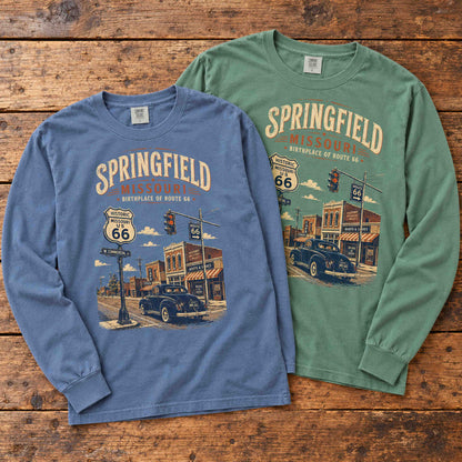 Blue Jean and Light Green Springfield Missouri Route 66 long sleeve graphic tees arranged flat on a wooden table.