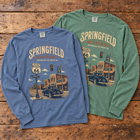 Blue Jean and Light Green Springfield Missouri Route 66 long sleeve graphic tees arranged flat on a wooden table.