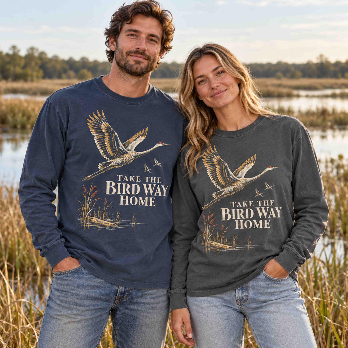 Man and woman wearing Navy and Pepper sandhill crane long sleeve shirts near a wetland.