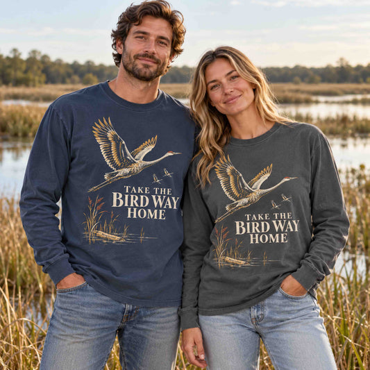 Man and woman wearing Navy and Pepper sandhill crane long sleeve shirts near a wetland.