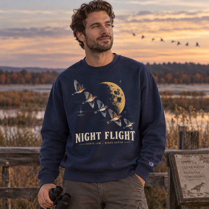 Woman wearing a Black Night Flight Bird Migration Champion sweatshirt at a wetland birdwatching overlook at sunset