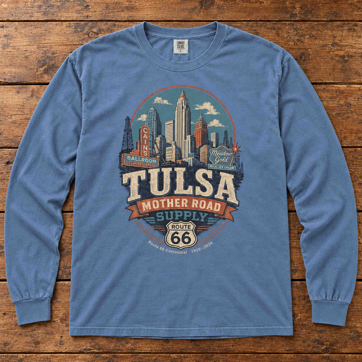 Blue Jean Tulsa Oklahoma Route 66 long sleeve tee laid flat on wood, showing skyline, vintage signs and Mother Road Supply artwork.
