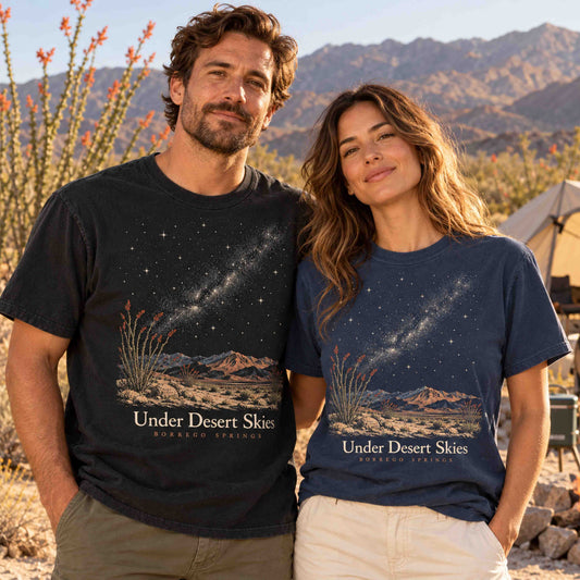 Man and woman wearing Being is Good Under Desert Skies Borrego Springs T-shirts in Black and Navy in a desert campsite setting.