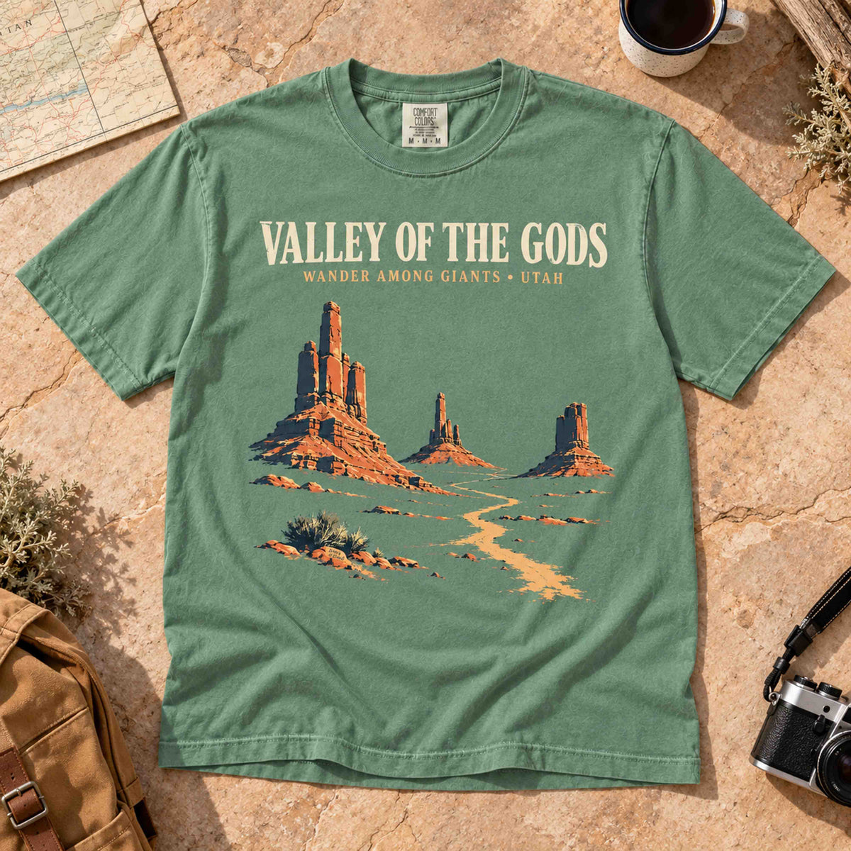 Woman wearing a Light Green Valley of the Gods Utah graphic T-shirt with denim shorts in a red rock desert landscape.