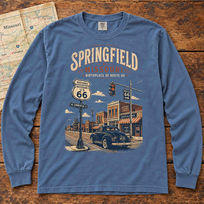 Blue Jean Springfield Missouri Route 66 long sleeve tee laid flat on wood, showing a classic car, storefronts and historic highway shield.