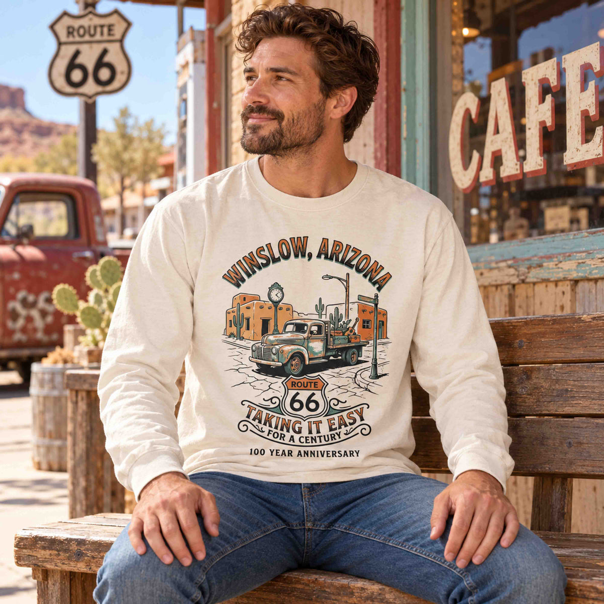 Man seated on a wooden bench wearing an Ivory Winslow Route 66 long sleeve graphic tee.