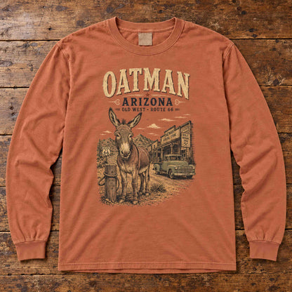 Yam Oatman Arizona Route 66 long sleeve tee laid flat on wood, showing burro, vintage truck and storefront artwork.