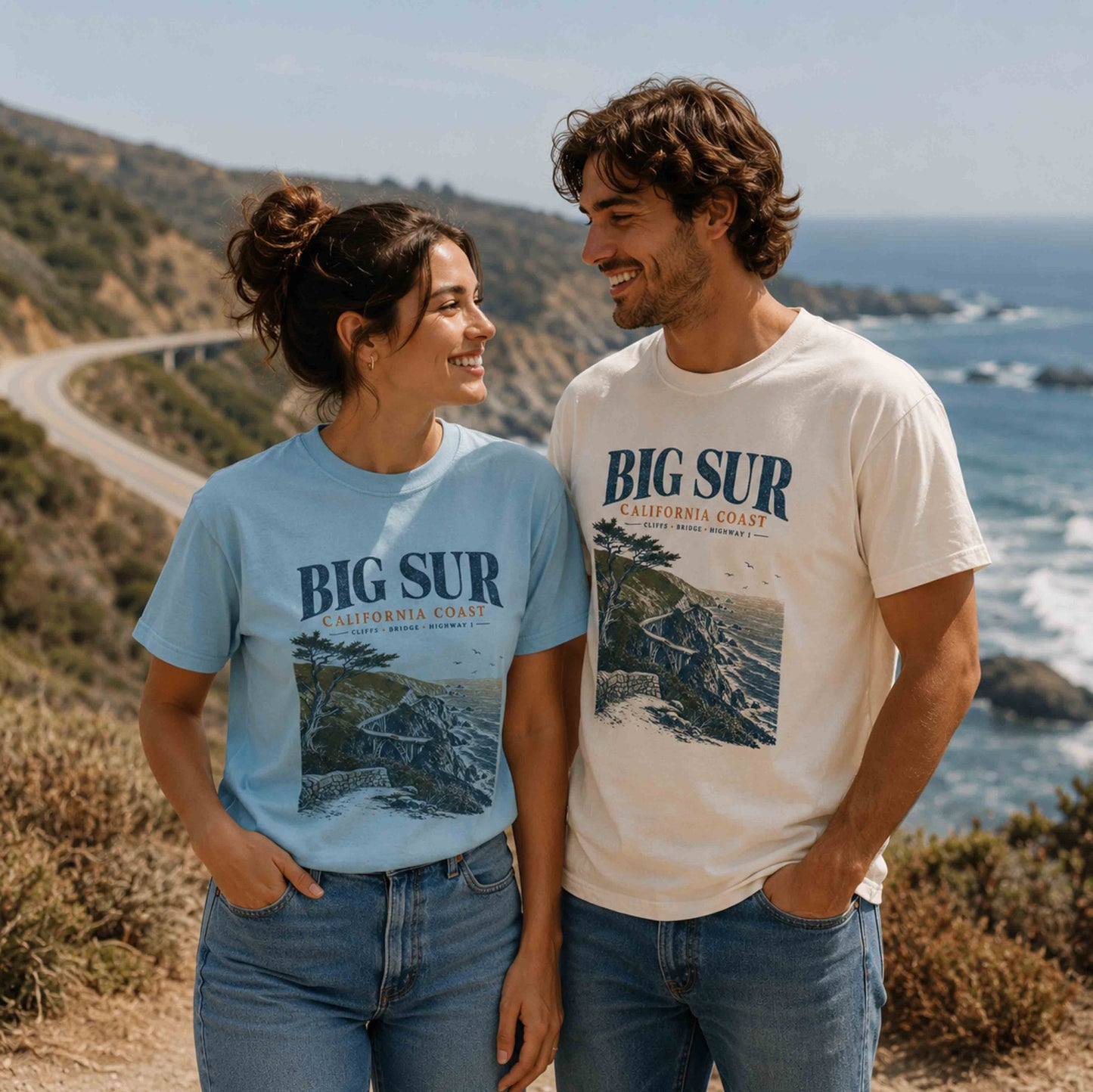 Couple wearing Big Sur California Coast graphic t-shirts in Chambray and Ivory overlooking Highway 1
