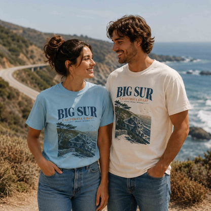 Couple wearing Big Sur California Coast graphic t-shirts in Chambray and Ivory overlooking Highway 1